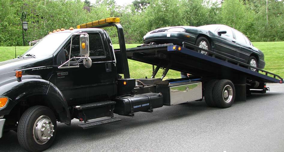 A flatbed tow truck transporting a passenger car